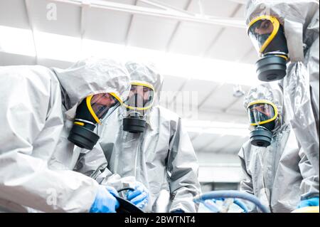 Low angle view of sanitation workers preparing for decontamination in warehouse Stock Photo