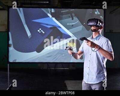 Man wearing VR glasses and using joysticks in virtual training class Stock Photo