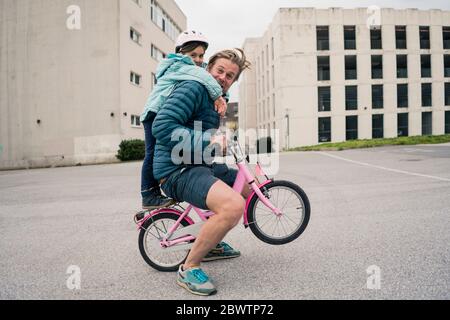 Playful father with daughter on her bicycle Stock Photo