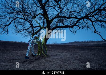 Spacewoman discovering a tree in the evening Stock Photo