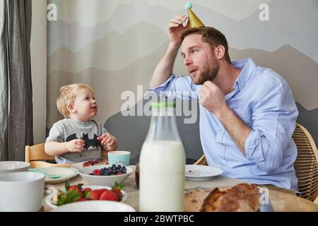 Father and little son having fun at breakfast table Stock Photo