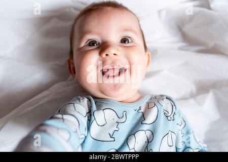 Baby girl teething, lying on bed Stock Photo