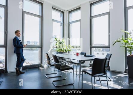 Businessman standing at thw window in office Stock Photo