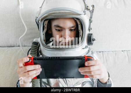 Boy playing video game on a games console, wearing space hat Stock Photo