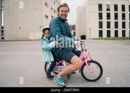 Playful father with daughter on her bicycle Stock Photo