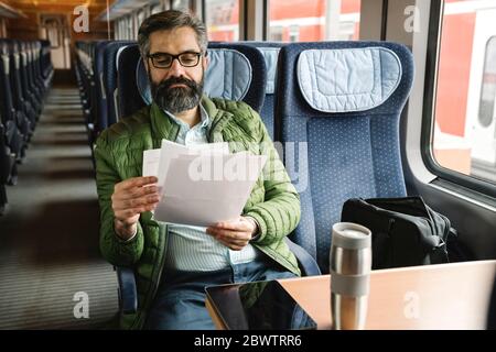 Man sitting in train reading documents Stock Photo