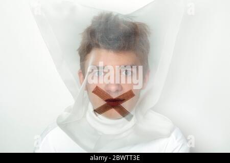 Portrait of teenage boy wearing  transparent mask with cross on his mouth Stock Photo