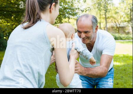 Senior man spending time with his adult daughter and his granddaughter in a park Stock Photo