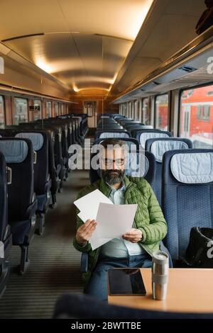Man sitting in train reading documents Stock Photo