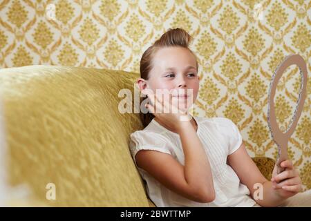 Portrait of girl on a couch looking in cardboard mirror Stock Photo
