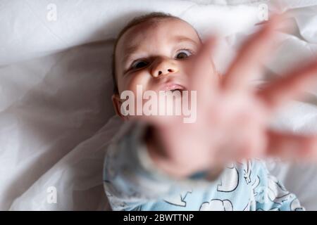 Baby girl teething, lying on bed Stock Photo