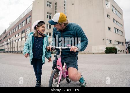 Happy father with daughter on her bicycle Stock Photo