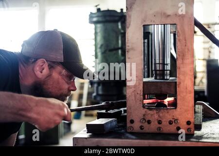 Knife maker working with damask steel at hydraulic sledge-hammer Stock Photo