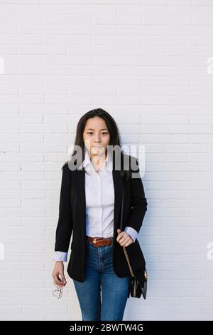 Portrait of young businesswoman standing in front of white wall Stock Photo