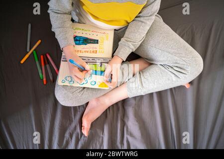 Crop view of drawing boy sitting on bed Stock Photo
