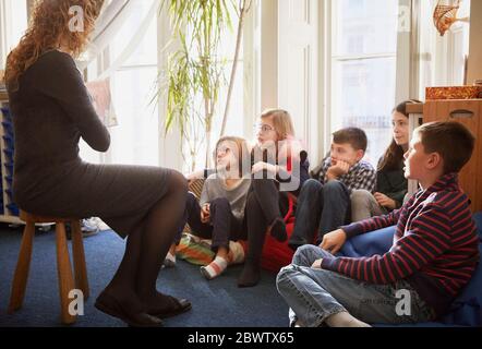 Children in a classroom during story time with the teacher Stock Photo