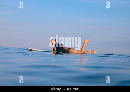 Happy woman lying on surfboard in the sea, Bali, Indonesia Stock Photo