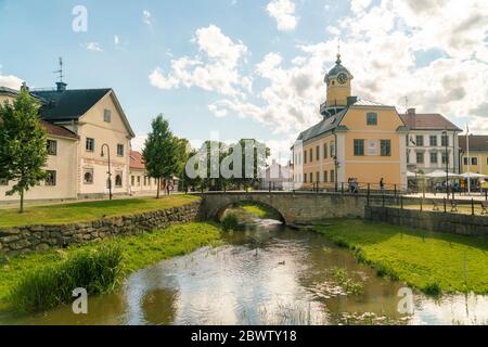 Sweden, Ostergotland, Soderkoping, Arch bridge over small city canal with town hall in background Stock Photo
