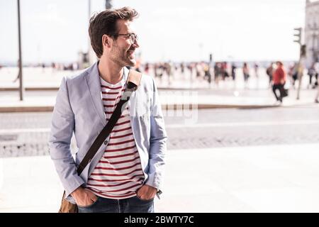 Smiling young man in the city looking sideways, Lisbon, Portugal Stock Photo