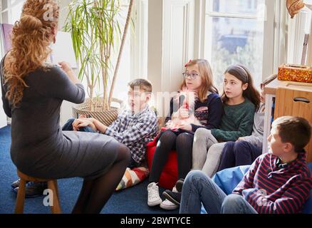 Children in a classroom during story time with the teacher Stock Photo