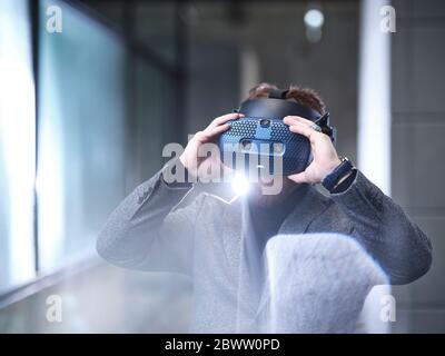 Man wearing VR glasses and headset in modern office Stock Photo