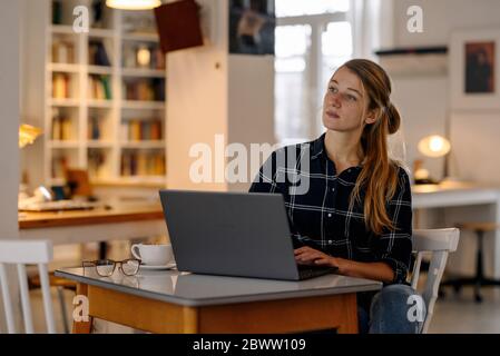 Young woman sitting at table using laptop Stock Photo