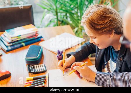 Father helping son doing homework at desk Stock Photo