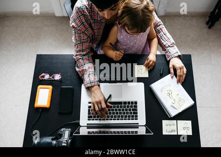 Mother working at home with her daughter, from above Stock Photo