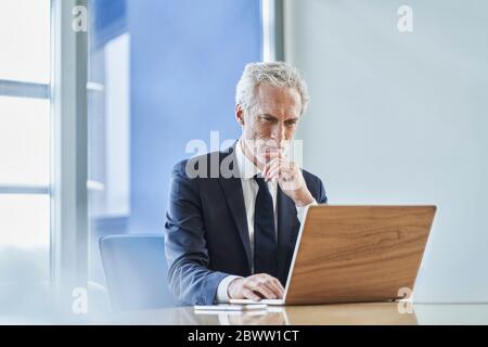 Focused businessman using laptop at desk in office Stock Photo