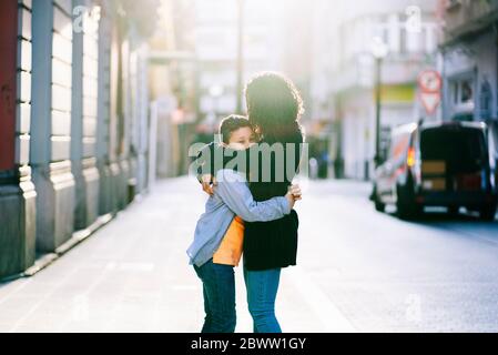 Mother and son hugging each other in the city Stock Photo