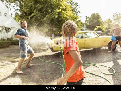 Friends washing yellow vintage car in summer having fun Stock Photo