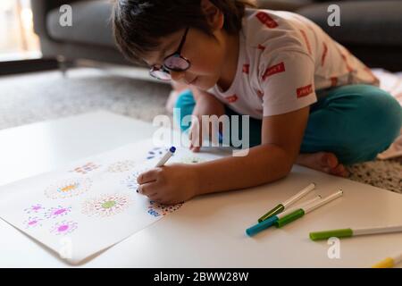 Boy sitting on the floor at home drawing flowers Stock Photo