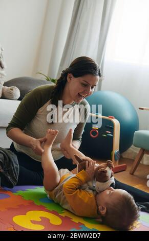 Mother playing with her little son on floor of the living room Stock Photo
