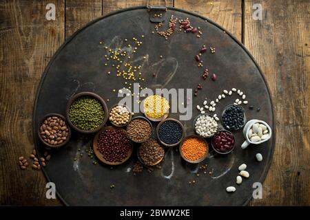 Bowls with various beans and lentils on rustic baking sheet Stock Photo