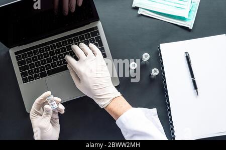Directly above shot of scientist analyzing medical sample while using laptop at desk in laboratory Stock Photo