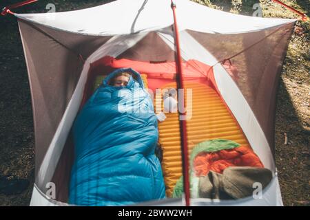 Young woman sleeping in sleeping bag in a tent Stock Photo