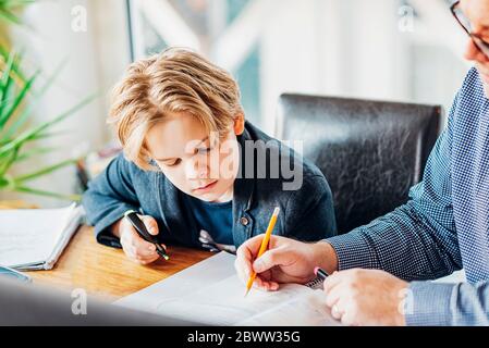 Father helping son doing homework at desk Stock Photo