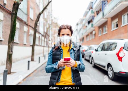 Woman wearing protective mask and using smartphone Stock Photo