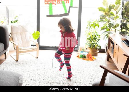 Full length of dancing while listening music through headphones in living room Stock Photo