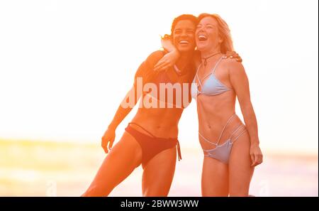 Two carefree women hugging on the beach at sunset, Costa Rica Stock Photo