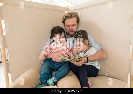 Father reading book to two daughters Stock Photo