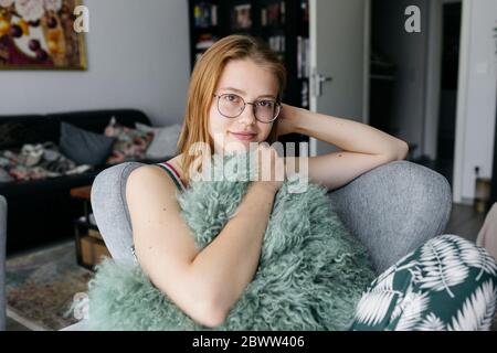 Portrait of smiling young woman sitting on armchair in the living room