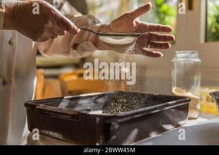 Hands of woman pouring bread crumbs into baking pan Stock Photo