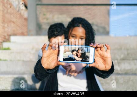 Woman's hands holding smartphone with selfie, close-up Stock Photo