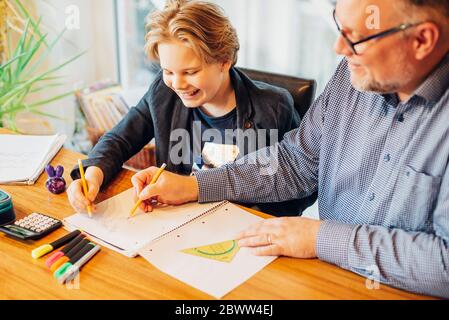 Father helping son doing homework at desk Stock Photo