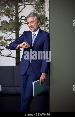 Mature businessman in office checking the time Stock Photo