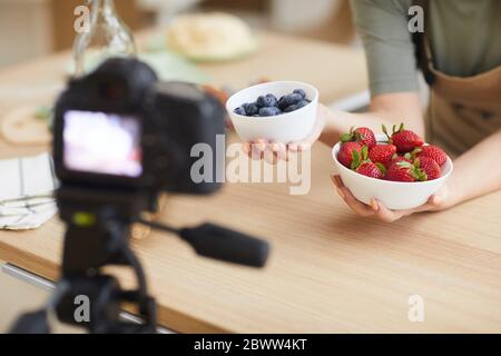 Close-up of woman holding two bowls with fresh berries in her hands and shooting the video Stock Photo