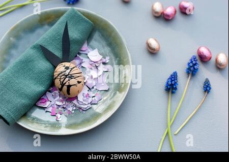 Germany, Plate, cloth napkin, chocolate eggs, grape hyacinths and Easter bunny made of eggshell Stock Photo