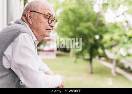 Senior man on balcony looking at distance Stock Photo