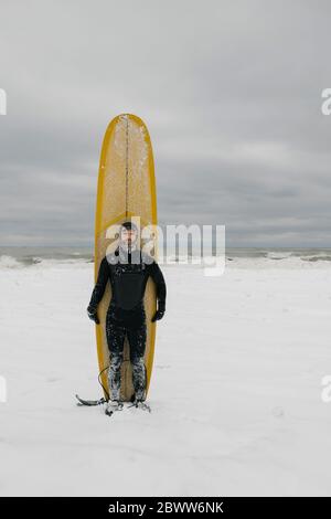 Surfer with surfboard in snow in Ontario, Canada Stock Photo